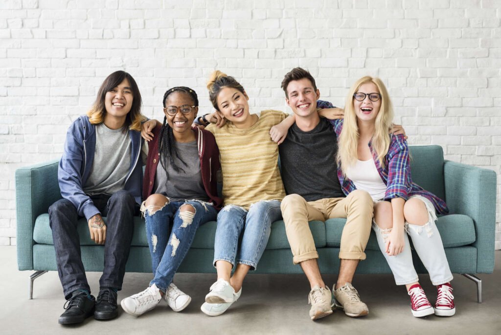 Diverse group of five teens sitting on a couch representing teenage mood swings or adolescent mood swings.